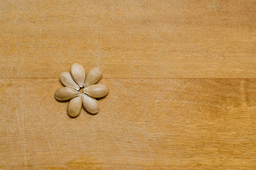 Pumpkin seeds forming a flower on a light wood surface