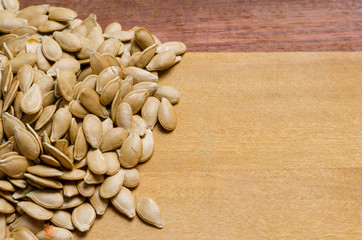 squash of pumpkin seeds on a two-colored wooden surface