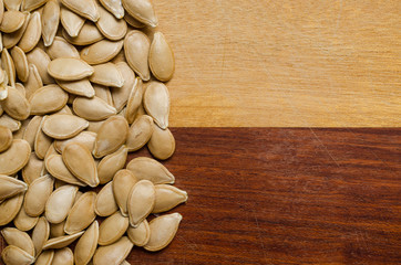 squash of pumpkin seeds on a two-colored wooden surface
