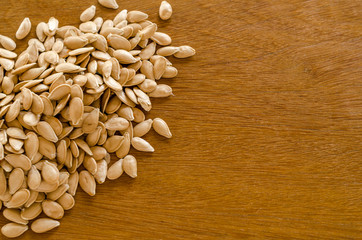 Pumpkin seeds huddled on a wooden surface