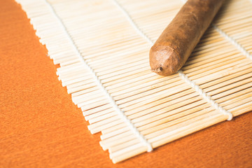 Fragrant cigar on white bamboo mat.