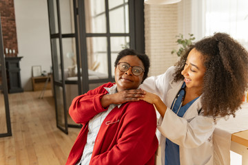 Dark-skinned woman wearing glasses feeling thankful to caring nurse