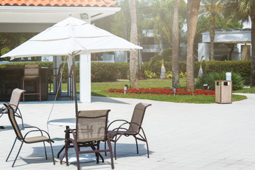 Сhaise lounge, coconut green palm trees under the sun,skyscrapers view, tropical background. Summer, holidays, luxury resort, tourism vacation