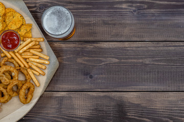 Diverse snacks with beer on dark wooden background. Top view, Empty space for text