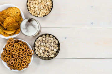 Beer and snacks on light wooden background. Empty space for text. Top view