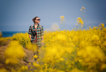 Travel to Jeju Island, South Korea, a young girl tourist walks on the background of blooming yellow fields and blue sea on a spring day. travel to Asia