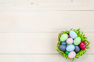 Easter eggs in basket on wooden background. Backdrop with empty space for text