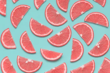 Kreatives Sommermuster mit Grapefruitscheiben auf pastellblauem Hintergrund. Minimales gesundes Essen, Farbtrendkonzept. Pop-Art-Stil. Ansicht von oben, flach liegend. © Kat Ka