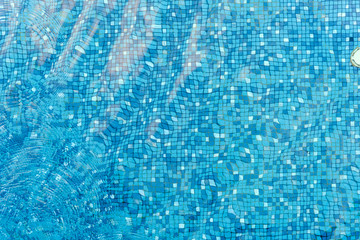 Fototapeta na wymiar Top view of water ripples on blue mosaic tiled. bottom of swimming pool. background