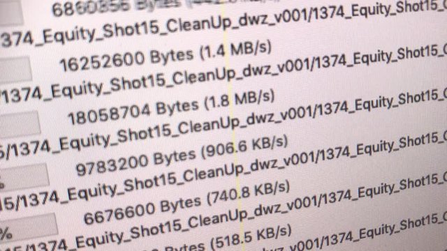 handheld super close shot of monitor showing growing upload bars, file names and percentages of a ftp program in German language. white background, black type, green bars, slight side angle view