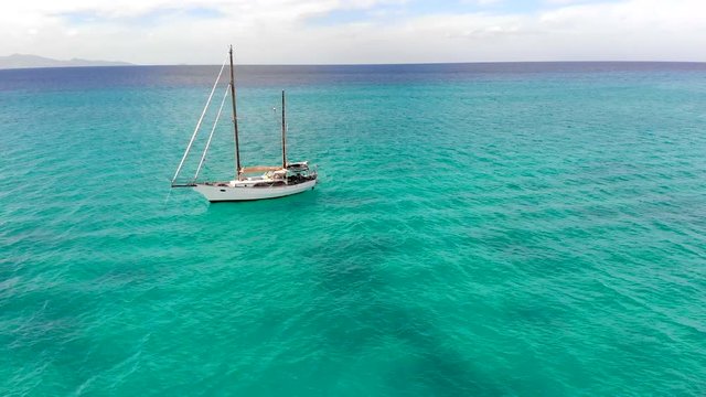 Awesome 360 drone shot over a white sail boat in the middle of the ocean