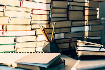 Laptop, stack of books, notebook, pencils in office background for education learning concept.