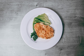 chicken fillet in cheese and lettuce on a white plate