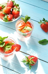 refreshing summer drinks with fresh strawberries  and mint on blue wooden surface, table, background. Copy space