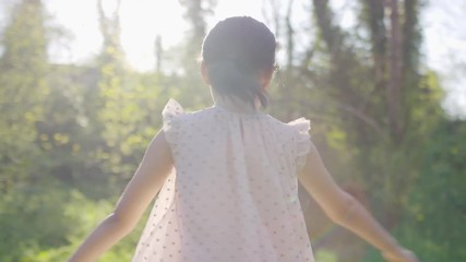 Young girl twirling in the sunlight, in slow motion