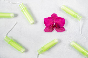 Cotton tampons with orchid on light grey background. Concept of critical days, menstruation or woman's health. Top view, flat lay.
