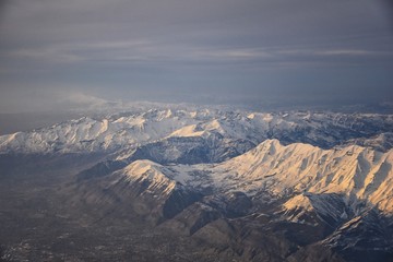 Aerial view from airplane of the Wasatch Front Rocky Mountain Range with snow capped peaks in winter including urban cities of Provo, Farmington Bountiful, Orem and Salt Lake City. Utah. United States