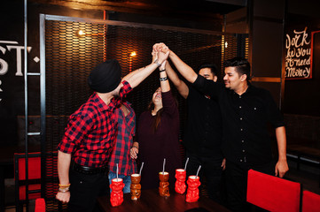  Group of indian friends having fun and rest at night club, drinking cocktails and giving high five...