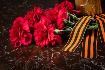 bouquet of red flowers and St. George ribbon, close-up on May 9th day