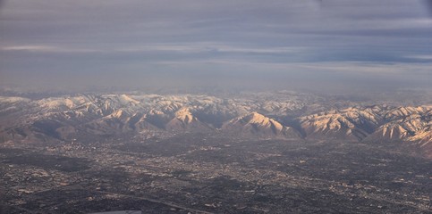 Aerial view from airplane of the Wasatch Front Rocky Mountain Range with snow capped peaks in winter including urban cities of Provo, Farmington Bountiful, Orem and Salt Lake City. Utah. United States