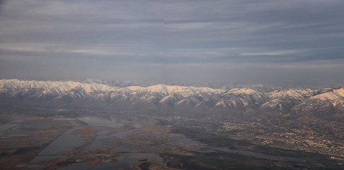 Aerial view from airplane of the Wasatch Front Rocky Mountain Range with snow capped peaks in winter including urban cities of Provo, Farmington Bountiful, Orem and Salt Lake City. Utah. United States