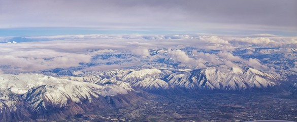 Aerial view from airplane of the Wasatch Front Rocky Mountain Range with snow capped peaks in winter including urban cities of Provo, Farmington Bountiful, Orem and Salt Lake City. Utah. United States