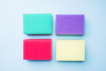 Cleaning colors sponges and brushes on blue background. Home cleaning concept. Top view, copy space.