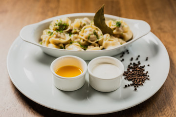 Meat dumplings or pelmeni served with sour cream and dill