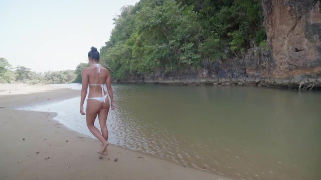 Slow Motion: Young Woman in Bikini Walking on Sandy Shore with Water and Cliff in El Limon, Dominican Republic