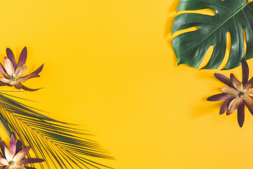 Summer composition. Tropical palm leaves and flowers on yellow background. Summer concept. Flat lay, top view, copy space