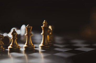 Golden Chess game King,Queen,Bishop staying on board,Business planing strong concept with dark background.