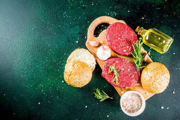 Raw beef burger cutlets, with spices and herbs, dark concrete background copy space