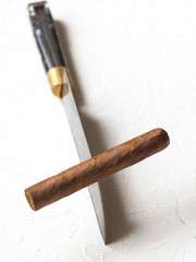 Cigar balancing on a knife edge. Dangers smoking.