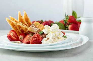 Waffles with strawberries and cream, mint and chocolate chips.