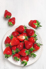 Fresh strawberries in plate on white wood