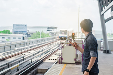Fototapeta premium BANGKOK THAILAND, April 7,2019 : Asian man passenger using smartphone and looking BTS in train station ,skytrain wait on BTS Skytrain station.