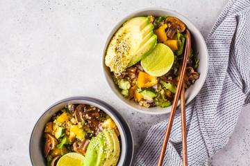 Quinoa salad with mushrooms, vegetables and avocados in gray bowl. Healthy vegan food concept.