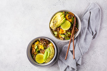 Quinoa salad with mushrooms, vegetables and avocados in gray bowl. Healthy vegan food concept.