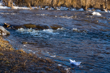 A paper boat on a turbulent stream of water struggles with the flow. Small paper boat is flowing...