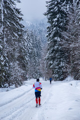 A man running in the forest with snow in the winter