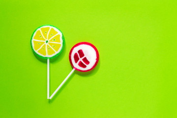 Sweet tasty lollipops on green background. Minimal flat lay with copy space