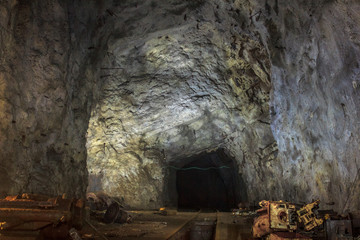 Fototapeta na wymiar Horizontal trunk of underground mine with high arches and remnants of mine equipment near the narrow gauge railway
