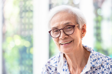 Close up asian elderly woman in glasses showing healthy straight teeth,portrait senior woman smiling feeling happy,beautiful female looking at camera in home