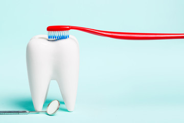 Oral dental hygiene. Dental mirror near healthy white tooth model with toothbrush on light blue...