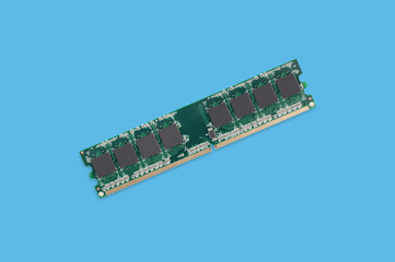 Green stick of RAM memory for computer with electronics components on blue table. Top view....