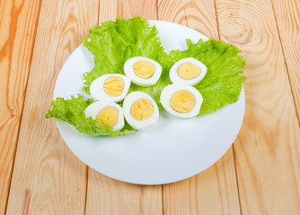 Halves of boiled chicken eggs on lettuce on dish