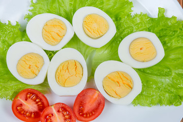 Halves of boiled chicken eggs and cherry tomatoes on lettuce