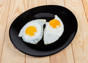 Two fried eggs prepared sunny side up on black dish