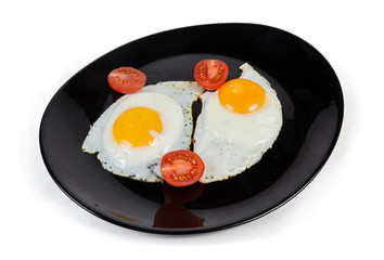 Fried eggs prepared sunny side up and tomatoes on dish