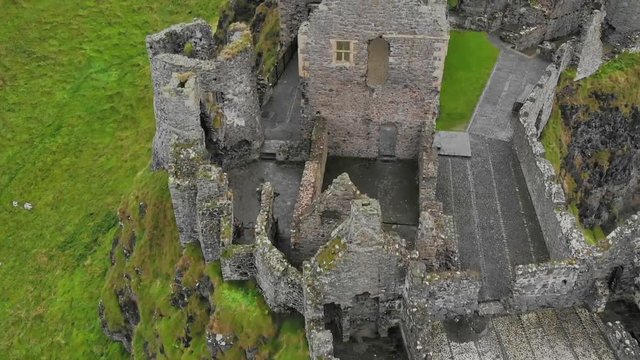 Close aerial top down travel shot over the Dunluce Castle ruins in Northern Ireland